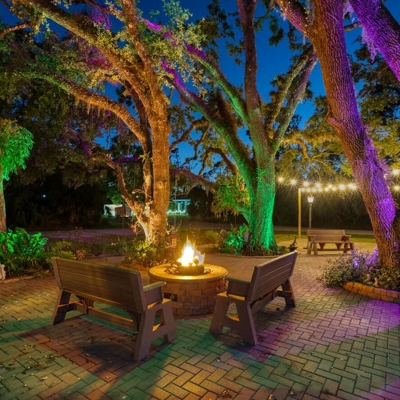 Backyard ambiance around a fire pit with color-changing lighting. Photo