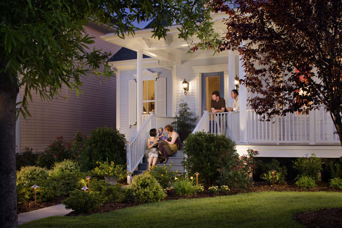 family on the porch of a house that is lit by OLP lighting 