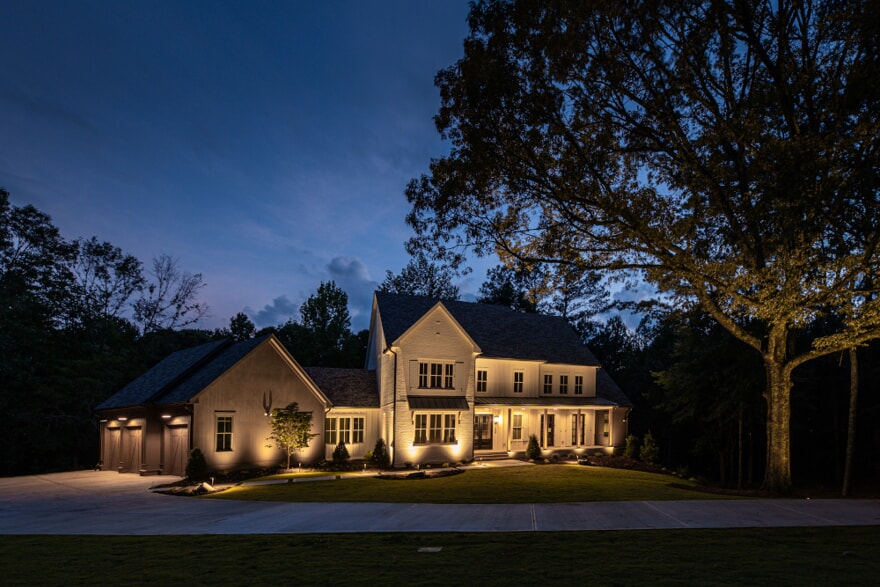 landscape lighting in front of large white house