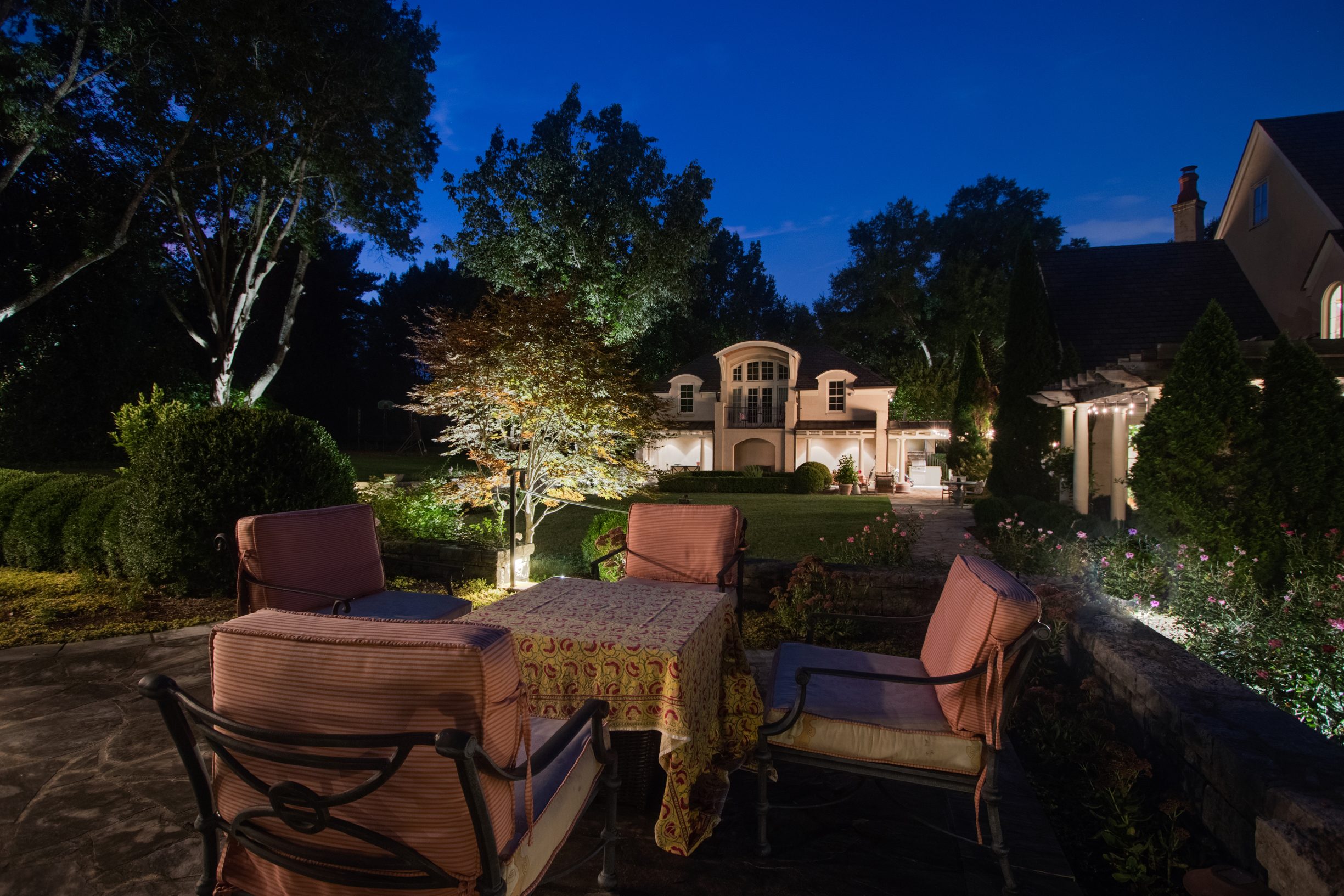A patio with chairs and a table in front of a houseDescription automatically generated