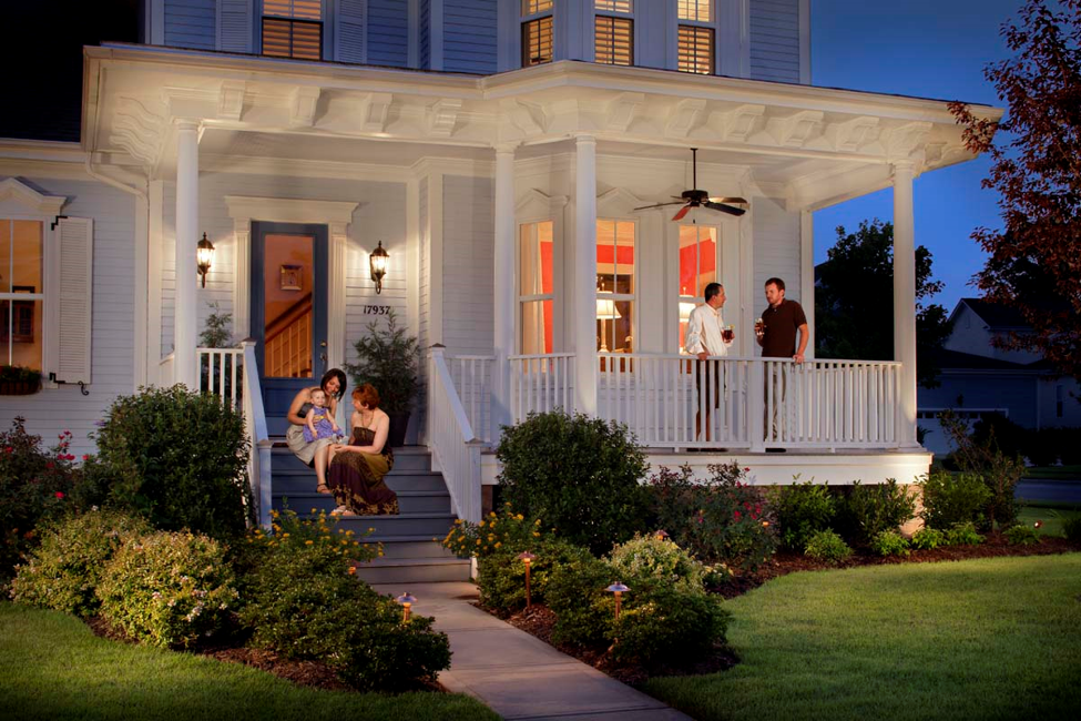 front porch lighting of a white house with people sitting on the porch