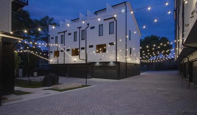 Townhomes with overhead string lighting above the ally and garages