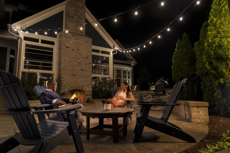 Overhead outdoor lighting above 2 people sitting on a patio