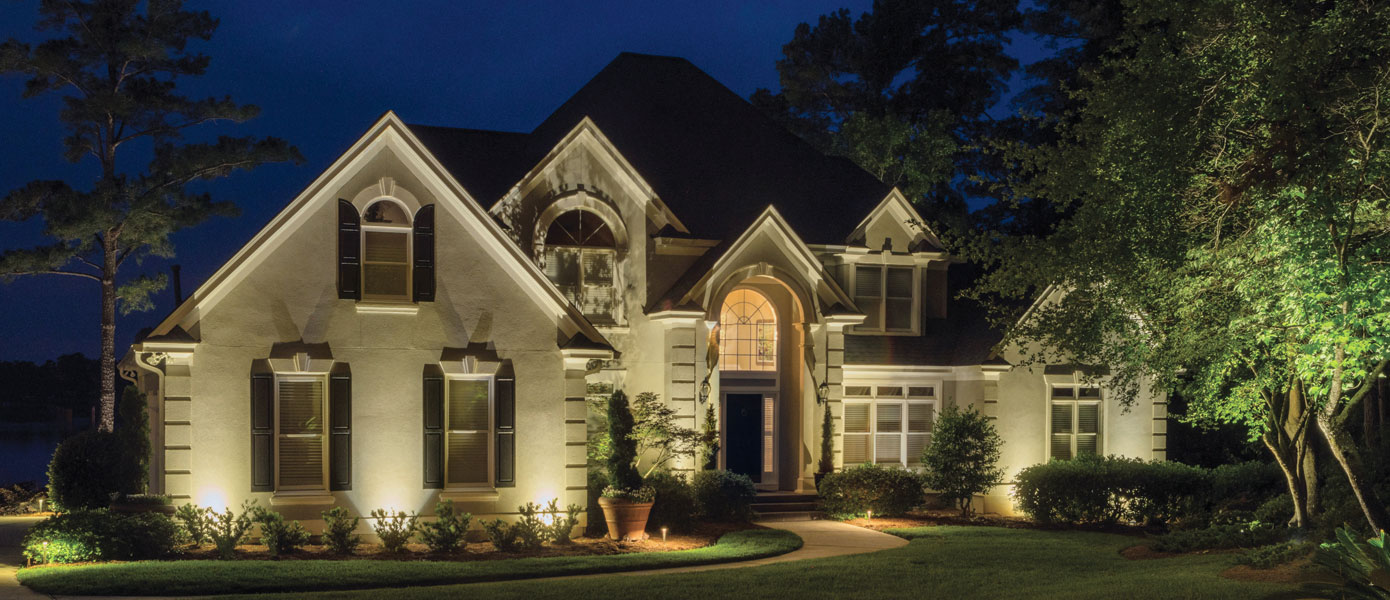 two-story house and landscaping lit at night