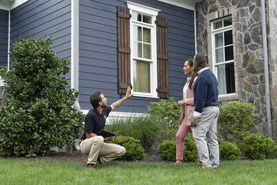 A group of people standing in front of a houseDescription automatically generated with medium confidence