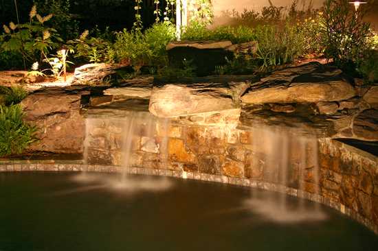 water feature lighting draws attention to the waterfall as the focal points of your yard