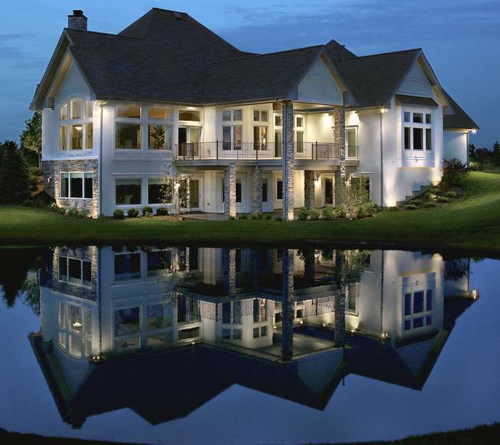House with outdoor lighting and reflection seen on water
