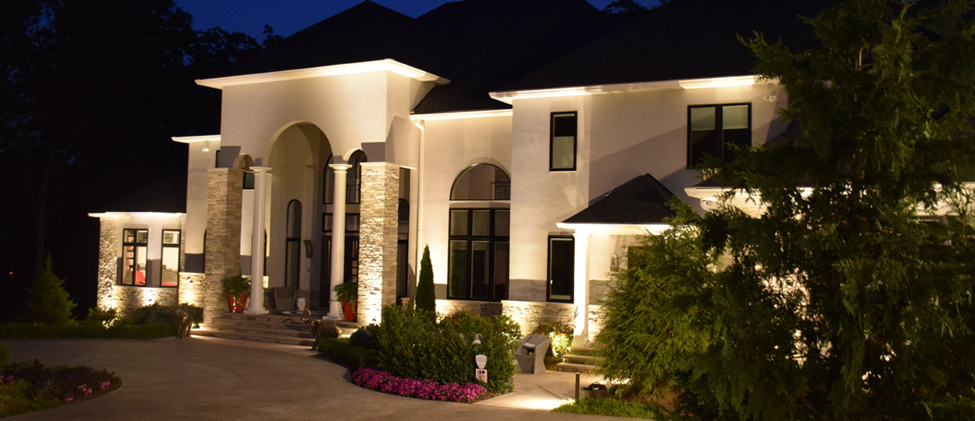 a white home with illumination lighting on the driveway and front porch 