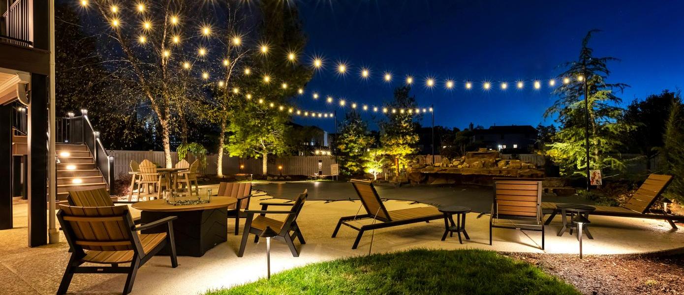 A patio area with chairs and a pool at night

Description automatically generated
