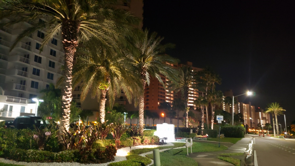 Front of a condo building with palm trees illuminated by OLP lighting
