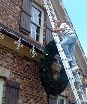 Man on a ladder putting up Christmas lights