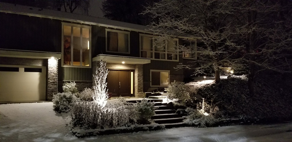 The front of a home, covered in snow at nighttime
