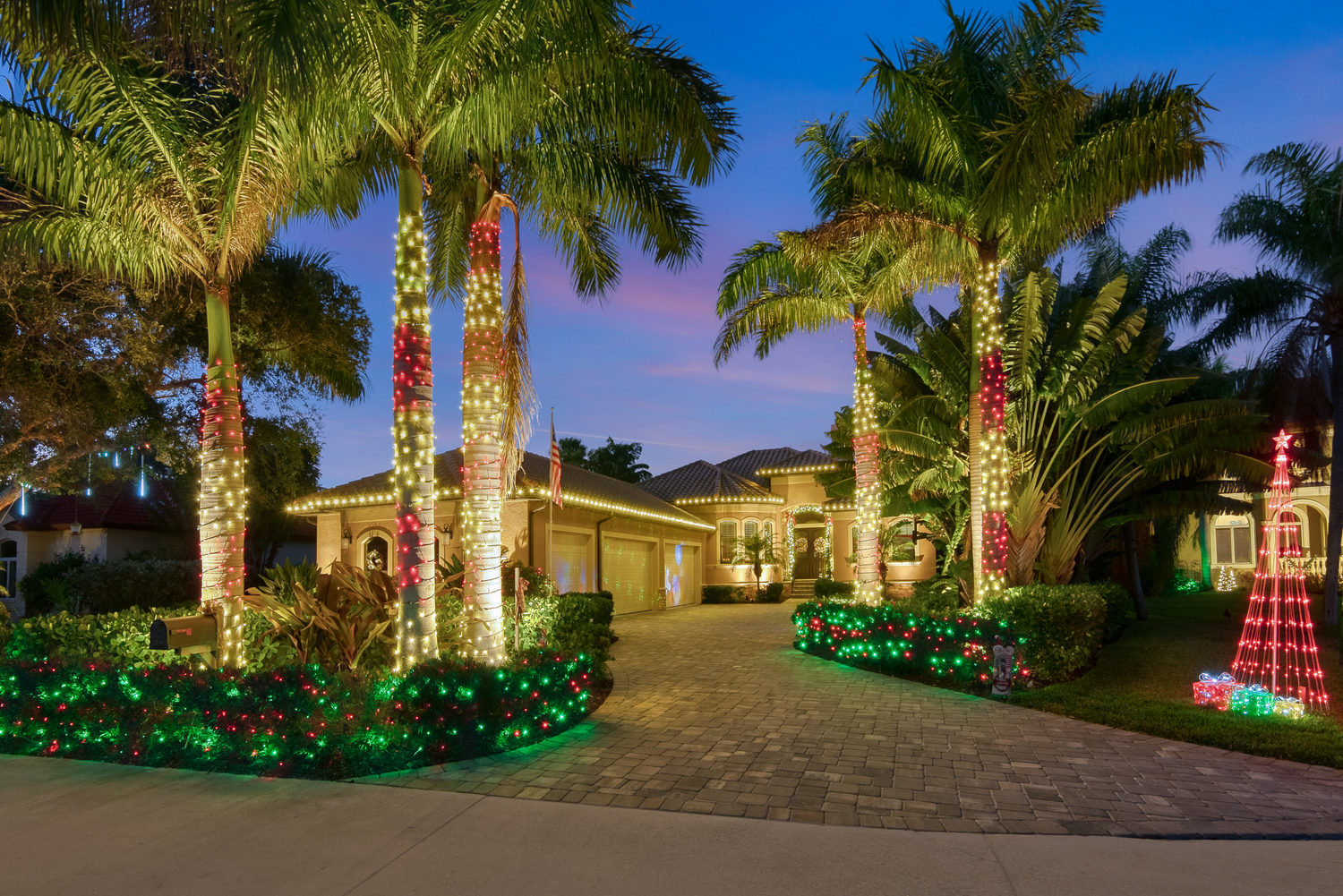 A home in Irvine with Christmas lights on its exterior, palm trees, and landscape
