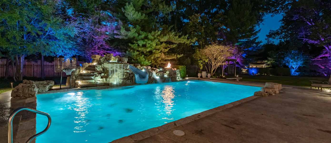 A pool with lights and treesDescription automatically generated