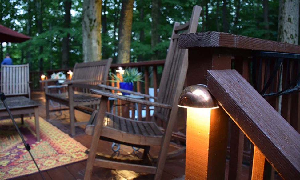 Deck decorated with chairs, plants, a rug and outdoor lighting