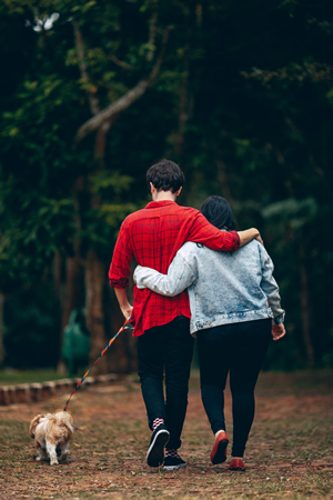 man and woman walking their dog outside