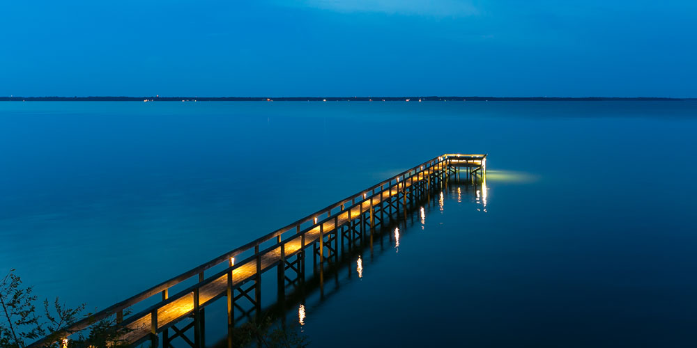 Beautifully lit dock leading out to a lake