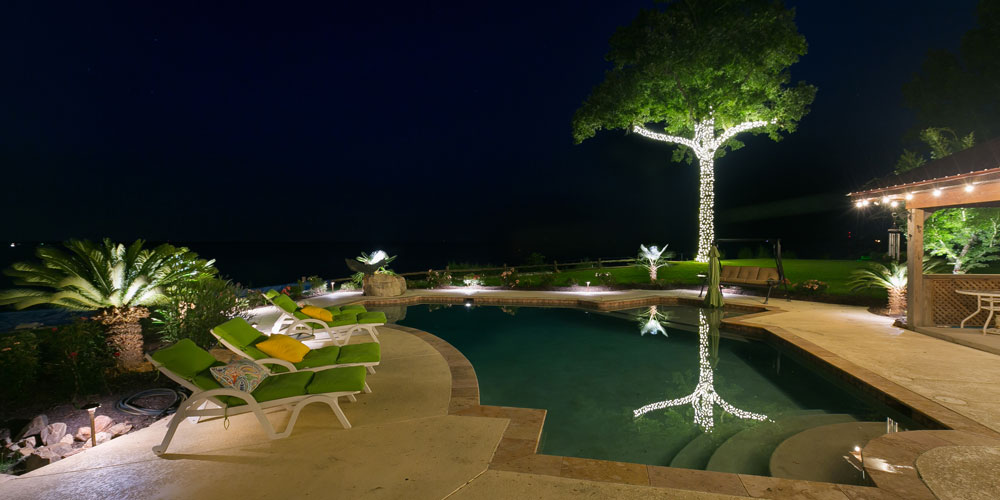 Pool and deck with lounge chairs, all lit by special lighting