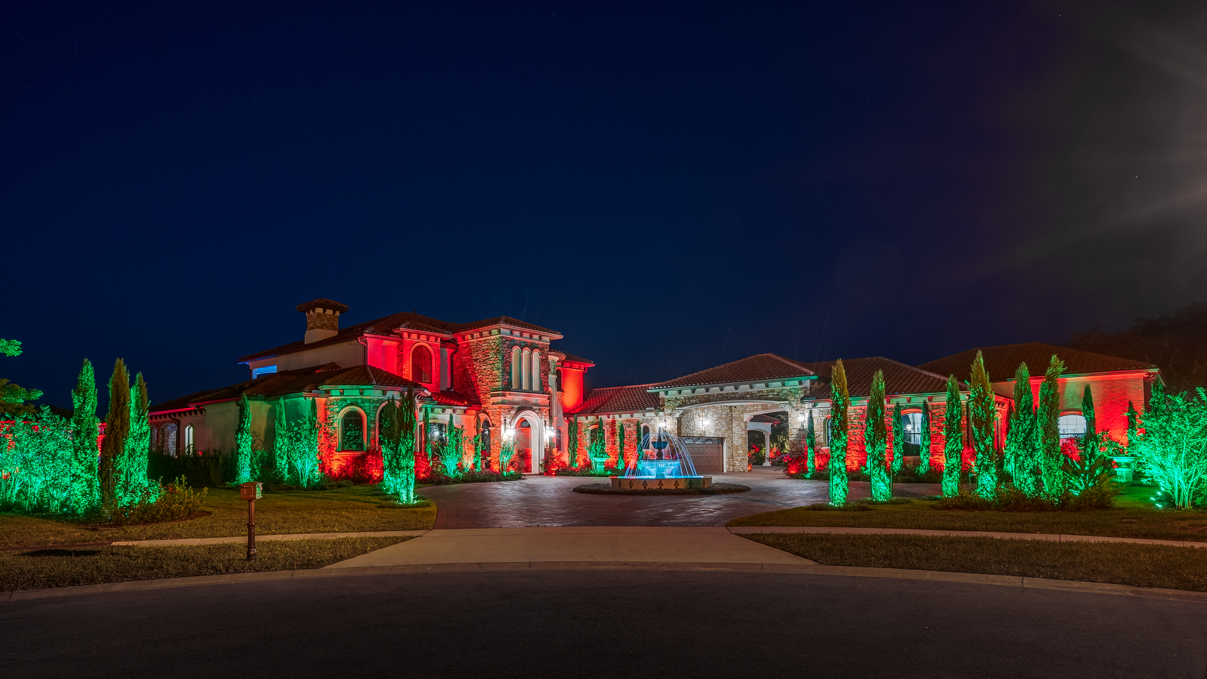 home with fountain, trees and lights