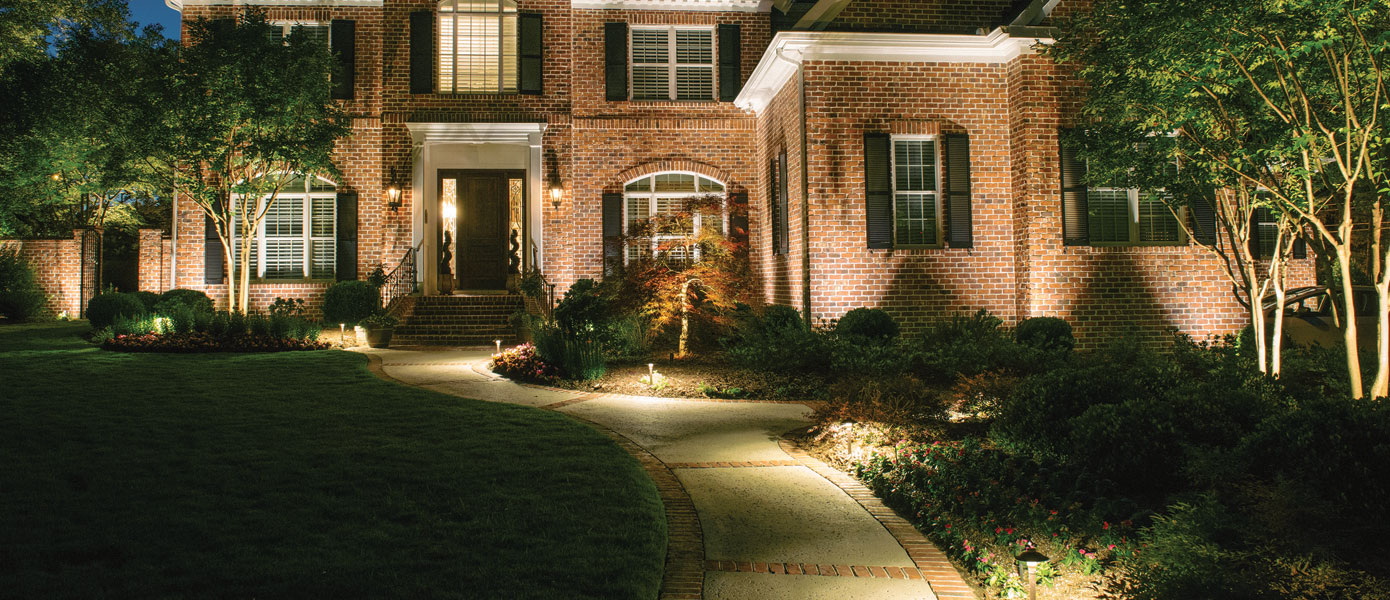 A brick house with a walkway and lawnDescription automatically generated