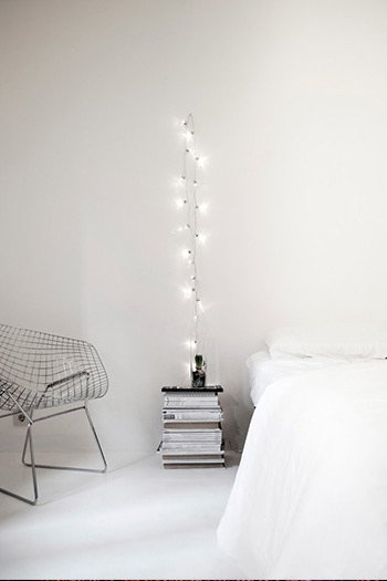 String lights creating a minimalist lamp, saving space on nightstand